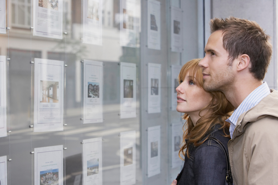 A couple looking at house listings in an estate agent's window