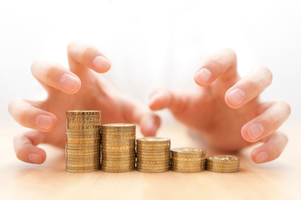 Two hands grabbing towards a pile of money