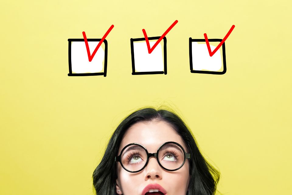 A woman looking up at a graphic depicting three boxes with big red ticks inside